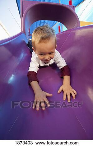 Stock Image - fort lauderdale, florida, united states of america; a young boy going down the slide at a playground. Fotosearch