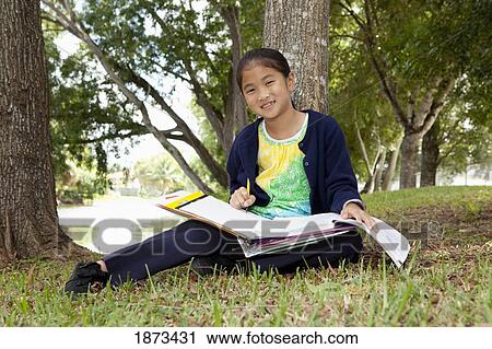 Stock Image - fort lauderdale, florida, united states of america; a girl doing school work in the park. Fotosearch