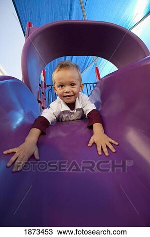 Stock Image - fort lauderdale, florida, united states of america; a young boy playing on a slide at the playground. Fotosearch
