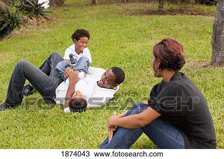 Stock Image - fort lauderdale, florida, united states of america; a father playing with his sons while their mother watches. Fotosearch