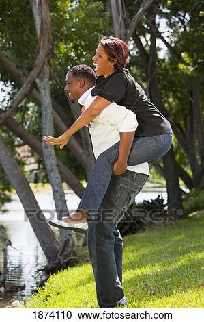 Stock Image - fort lauderdale, florida, united states of america; a man holding a woman on his back. Fotosearch