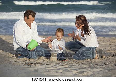 Stock Image - fort lauderdale, florida, united states of america; a family playing in the sand on the beach. Fotosearch