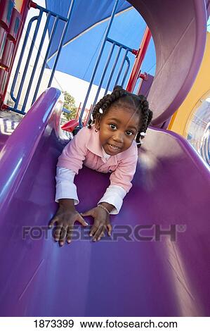 Stock Photo - fort lauderdale, florida, united states of america; a young girl going down the slide at a playground. Fotosearch