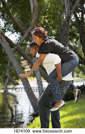 Stock Photo - fort lauderdale, florida, united states of america; a man holding a woman on his back. Fotosearch