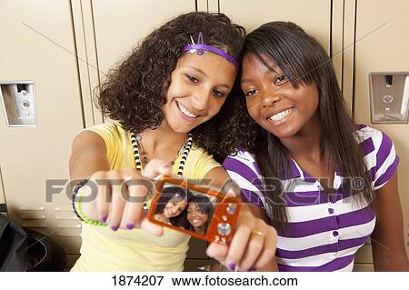 Stock Photo - fort lauderdale, florida, united states of america; two teenage girls sitting in a school hallway taking a picture of themselves. Fotosearch