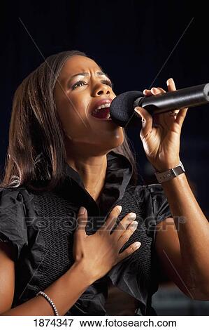 Stock Photo - fort lauderdale, florida, united states of america; a woman singing in a microphone. Fotosearch