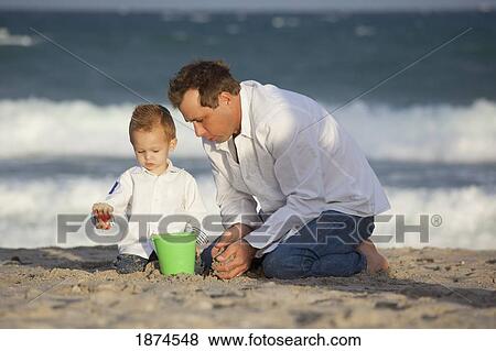 Stock Photo - fort lauderdale, florida, united states of america; a father and son playing in the sand on the beach. Fotosearch