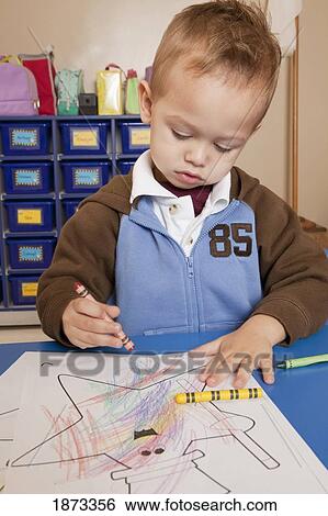 Stock Photograph - fort lauderdale, florida, united states of america; a young boy coloring at a table in a classroom. Fotosearch