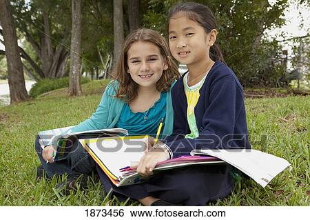 Stock Photograph - fort lauderdale, florida, united states of america; two girls doing school work in a park. Fotosearch