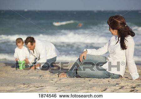 fort lauderdale, florida, united states of america; a father and son playing in the sand on the beach while the mother watches View Large Photo Image Stock Photograph - fort lauderdale, florida, united states of america; a father and son playing in the sand on the beach while the mother watches. Fotosearch