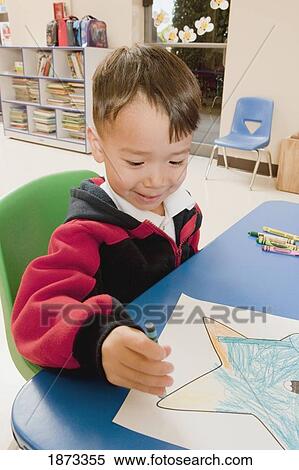Stock Photography - fort lauderdale, florida, united states of america; a young boy coloring at a table in a classroom. Fotosearch
