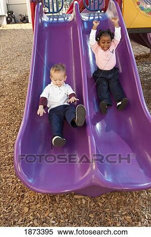 Stock Photography - fort lauderdale, florida, united states of america; two young children going down the slide at a playground. Fotosearch