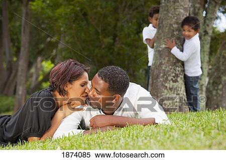 Stock Photography - fort lauderdale, florida, united states of america; a couple kissing while their sons watch. Fotosearch