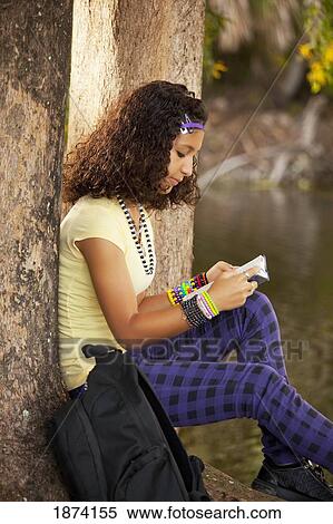 Stock Photography - fort lauderdale, florida, united states of america; a girl reading a book under a tree. Fotosearch