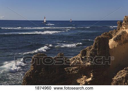 Stock Image - hawaii, united states of america; sailboats cruise along rugged coastal formations on the southeastern shore of kauai. Fotosearch