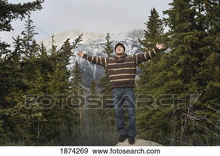 jasper national park, alberta, canada; a young man standing on a rock with arms raised and a mountain in the background View Large Photo Image Stock Photo - jasper national park, alberta, canada; a young man standing on a rock with arms raised and a mountain in the background. Fotosearch