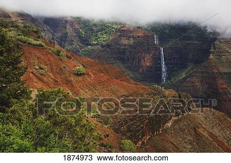 Stock Image - kauai, hawaii, united states of america; waipo'o falls in waimea canyon under a lifting cloud layer. Fotosearch