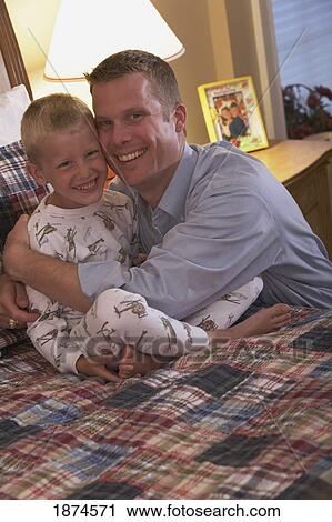 knoxville, tennessee, united states of america; a father hugging his son who is sitting on a bed wearing his pajamas View Large Photo Image Stock Image - knoxville, tennessee, united states of america; a father hugging his son who is sitting on a bed wearing his pajamas. Fotosearch