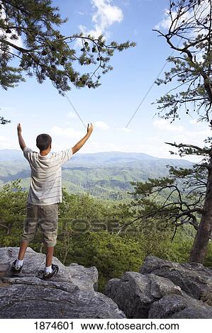 Stock Image - knoxville, tennessee, united states of america; a boy with his arms raised while overlooking the mountains. Fotosearch