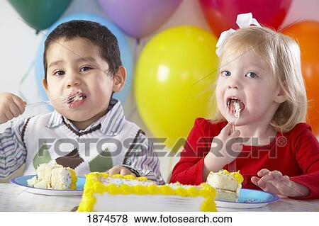 Stock Photo - knoxville, tennessee, united states of america; two children eating birthday cake. Fotosearch