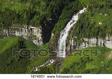 montana, united states of america; a large waterfall flows through summer vegetation near logan pass at glacier national park View Large Photo Image Stock Image - montana, united states of america; a large waterfall flows through summer vegetation near logan pass at glacier national park. Fotosearch