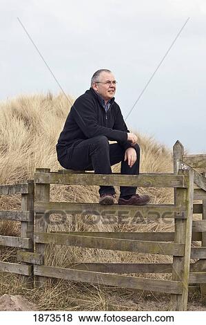 northumberland, england; a man sitting on a fence View Large Photo Image Stock Photo - northumberland, england; a man sitting on a fence. Fotosearch