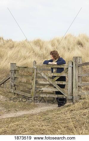 Stock Photo - northumberland, england; a woman leaning against a fence. Fotosearch