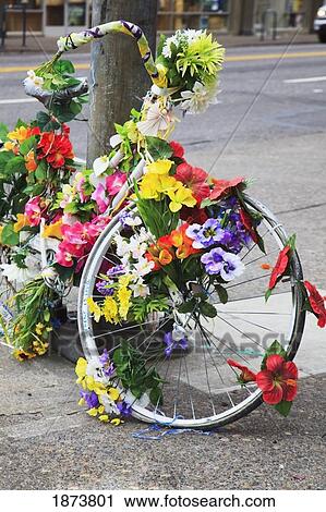 Stock Image - oregon, united states of america; a bike decorated with flowers leaning against a pole. Fotosearch
