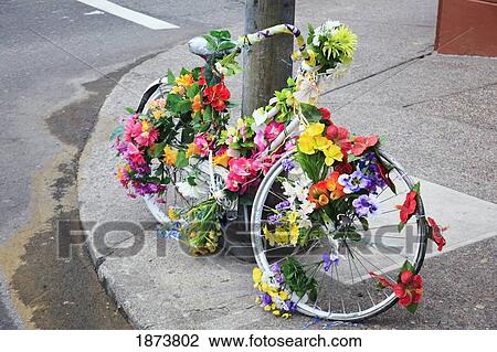 Stock Image - oregon, united states of america; a bike decorated with flowers leaning against a pole. Fotosearch