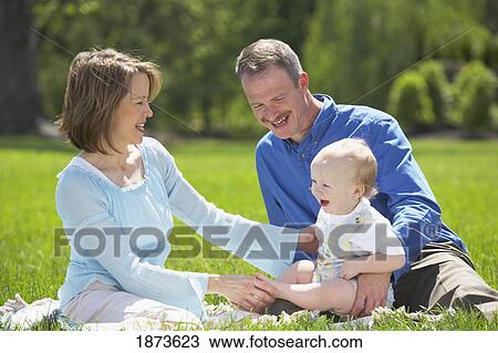 parents sitting on the grass with their young son View Large Photo Image Stock Image - parents sitting on the grass with their young son. Fotosearch