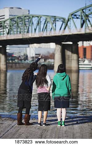 Stock Image - portland, oregon, united state of america; three friends looking at a bridge over a river. Fotosearch