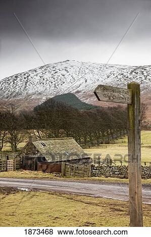 Stock Photo - scottish borders, scotland; a shed along the road with a snow covered hill in the background. Fotosearch
