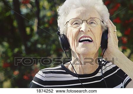 Stock Image - sherwood park, alberta, canada; a senior woman wearing headphones. Fotosearch