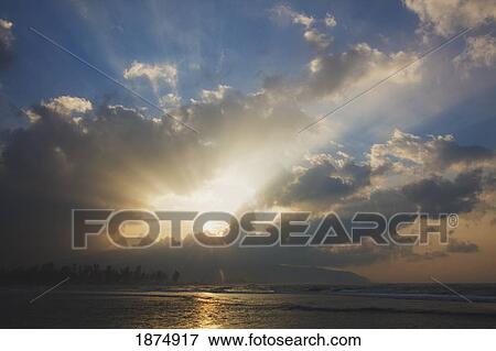 Stock Photo - sunburst through the clouds over the ocean. Fotosearch