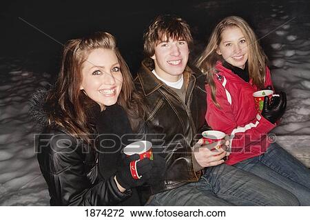 three young adults having a hot drink outside in the winter View Large Photo Image Stock Image - three young adults having a hot drink outside in the winter. Fotosearch