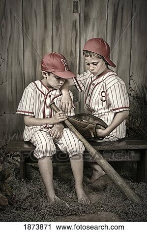 two boys in baseball uniforms sitting on a bench View Large Photo Image Stock Image - two boys in baseball uniforms sitting on a bench. Fotosearch