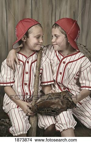 two boys wearing baseball uniforms and holding a bat and glove View Large Photo Image Picture - two boys wearing baseball uniforms and holding a bat and glove. Fotosearch