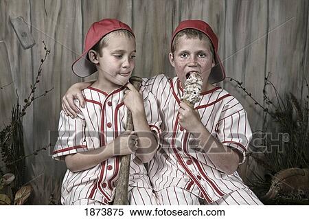two boys wearing baseball uniforms and one is eating an ice cream cone View Large Photo Image Stock Photography - two boys wearing baseball uniforms and one is eating an ice cream cone. Fotosearch
