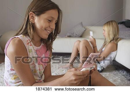 two girls playing their hand held games View Large Photo Image Stock Image - two girls playing their hand held games. Fotosearch