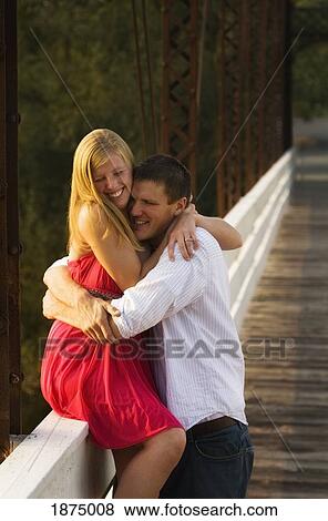 willmar, minnesota, united states of america; a woman sitting on a railing in an embrace with a man View Large Photo Image Stock Photo - willmar, minnesota, united states of america; a woman sitting on a railing in an embrace with a man. Fotosearch