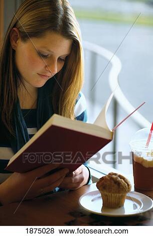 willmar, minnesota, united states of america; a girl sits with her muffin and drink at a restaurant table reading a book View Large Photo Image Stock Photo - willmar, minnesota, united states of america; a girl sits with her muffin and drink at a restaurant table reading a book. Fotosearch
