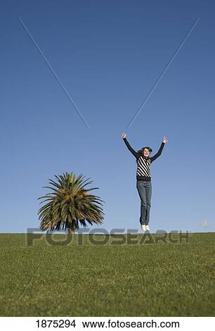 A girl jumps in the air at the top of the hill View Large Photo Image Picture - A girl jumps in the air at the top of the hill. Fotosearch