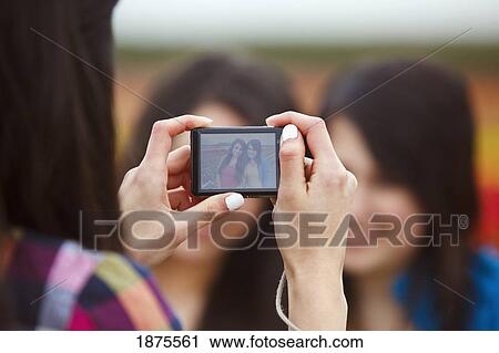 Stock Image - a girl taking a picture of her two friends. Fotosearch