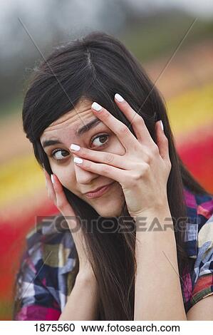 a girl with her hand over her face and peeking through her fingers View Large Photo Image Stock Image - a girl with her hand over her face and peeking through her fingers. Fotosearch