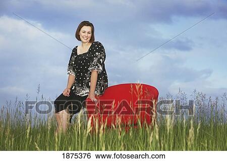 a woman sitting on a red chair in a field View Large Photo Image Stock Photograph - a woman sitting on a red chair in a field. Fotosearch