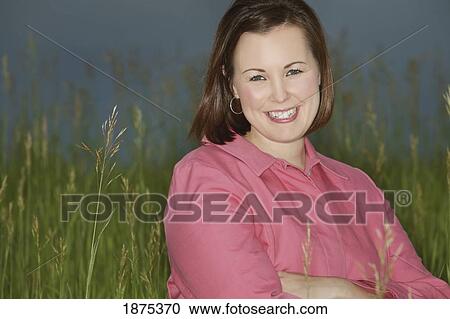 a young woman standing in tall grass View Large Photo Image Stock Image - a young woman standing in tall grass. Fotosearch