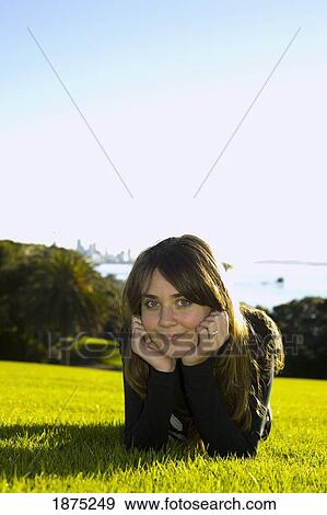 Stock Photo - new zealand; a teenage girl resting her face in her hands at the park. Fotosearch