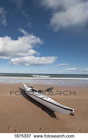 Stock Photo - northumberland, england; a kayak sitting on the sand on low newton beach. Fotosearch