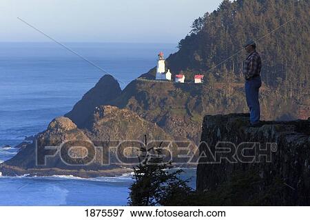 oregon, united states of america; a man standing on the edge of a cliff overlooking the pacific ocean with heceta head lighthouse in the background View Large Photo Image Stock Photo - oregon, united states of america; a man standing on the edge of a cliff overlooking the pacific ocean with heceta head lighthouse in the background. Fotosearch