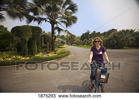 thailand; a woman riding her bike down the road View Large Photo Image Stock Image - thailand; a woman riding her bike down the road. Fotosearch